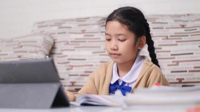用快乐做作业的亚洲小女孩，穿着学生幼儿园制服的泰国女孩，在家学习教育