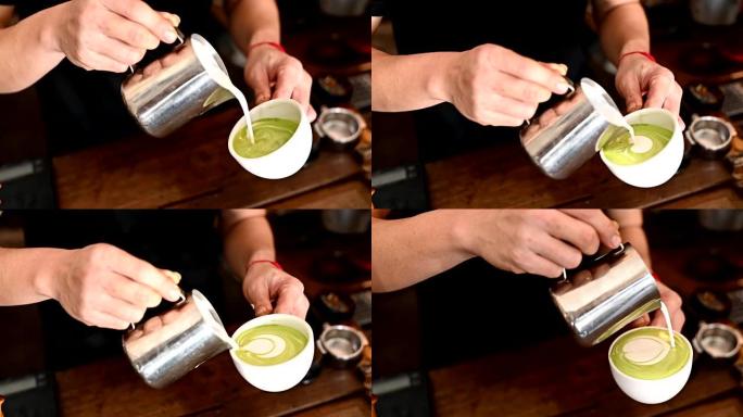 咖啡师手的短打镜头，试图将蒸牛奶倒入热绿茶中，以制作拿铁艺术。