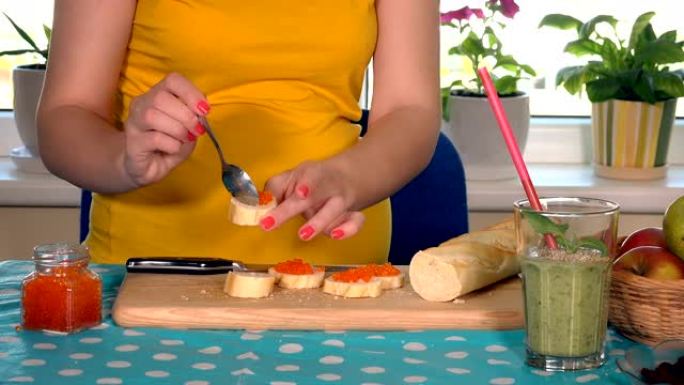 怀孕的妇女手带鱼子酱的三明治接力棒