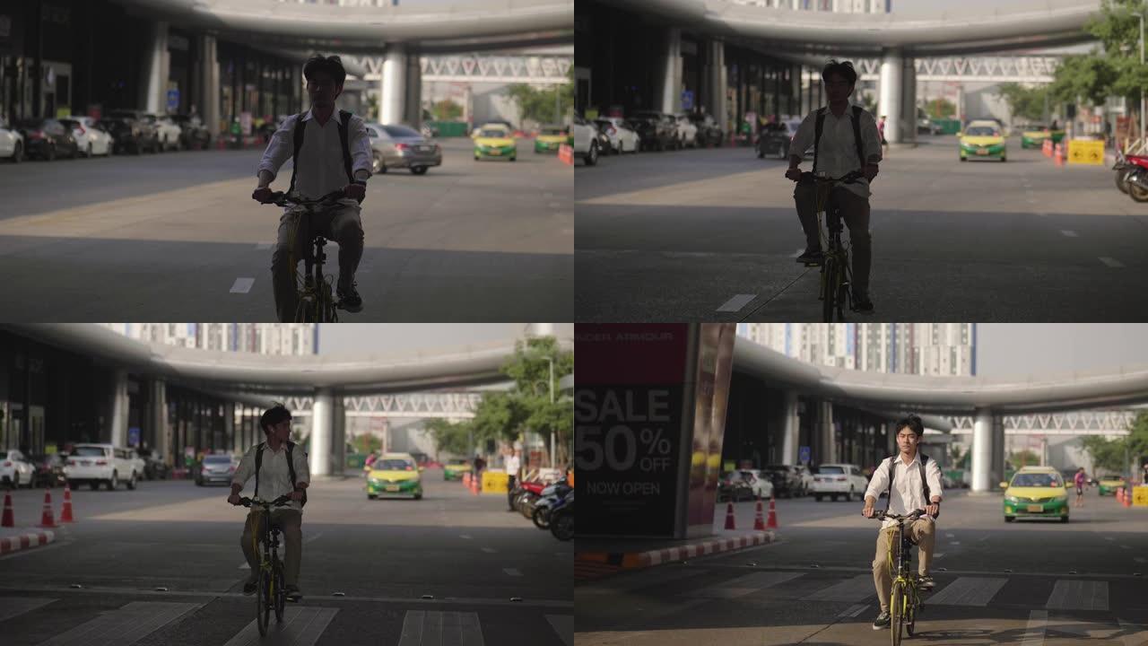 英俊的年轻人在城市的街道上驾驶自行车