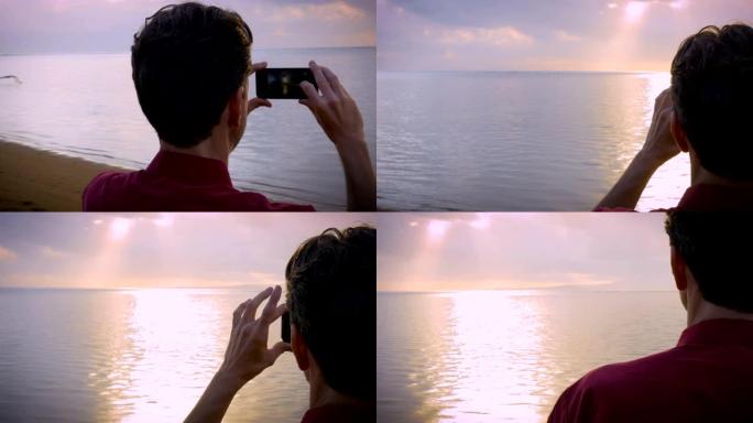 一名中年男子在海滩上拍摄智能手机照片的手持照片