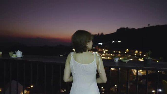 女人坐在山顶上放松，晚上欣赏壮丽的景色