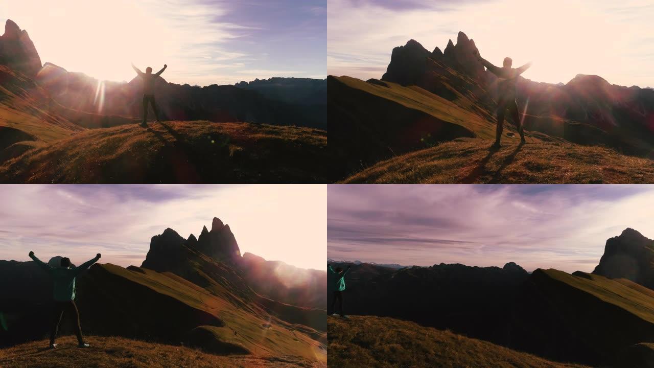 鸟瞰图。日出时，穿着运动服的年轻人在塞塞达山峰上举起手臂。Puez Odle，特伦蒂诺，多洛米蒂，意