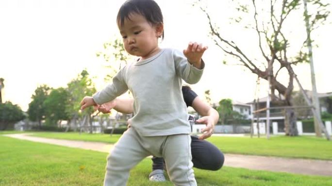 婴儿在母亲的帮助下在花园村迈出第一步