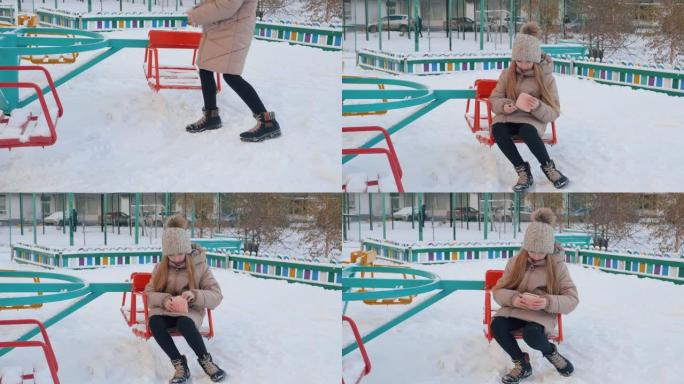 十几岁的女孩在冬季散步时在下雪的孩子们的地面上发现了钱包。年轻女孩拿钱包躺在冬天在城市的雪地上。