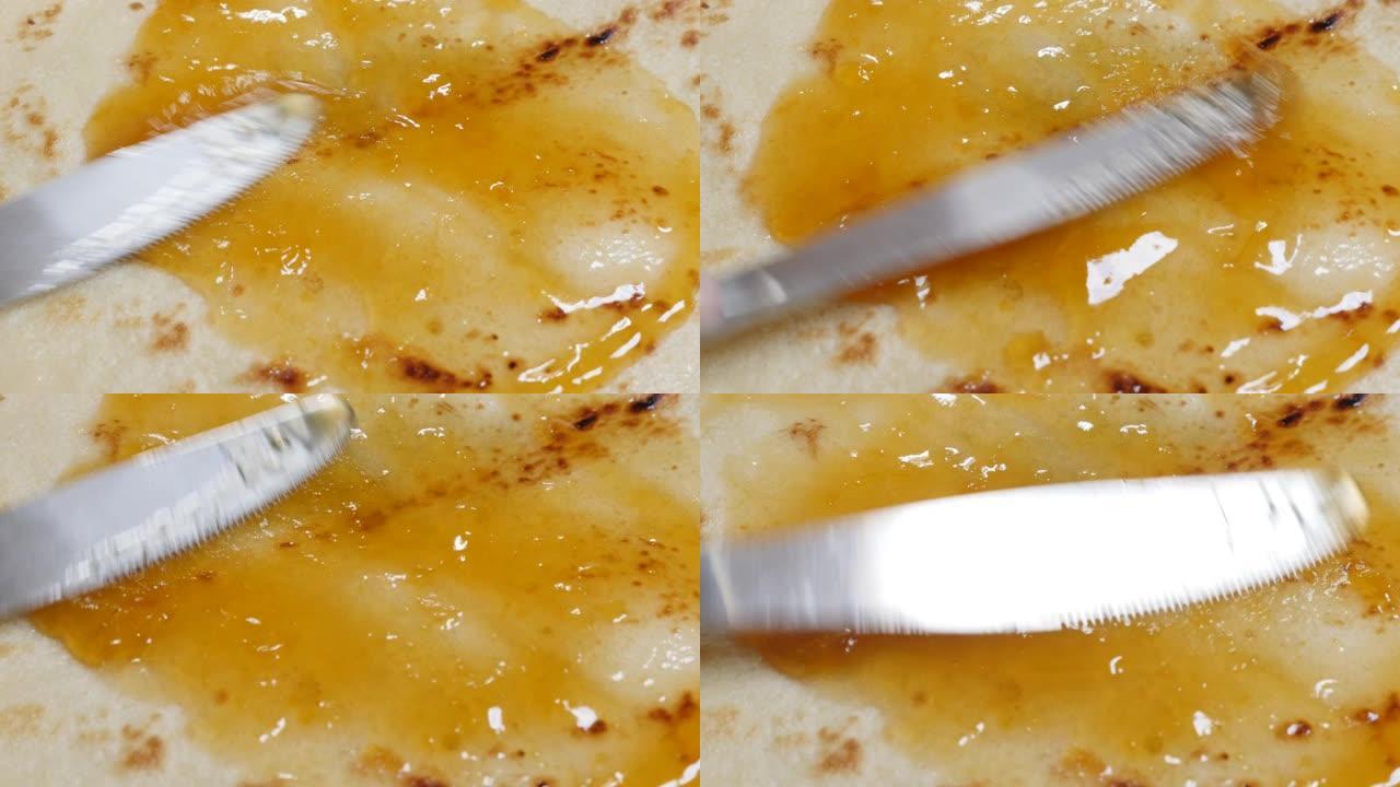 用刀铺在煎饼纹理上的桃子果酱特写4K