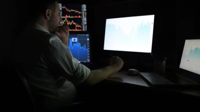 穿着白衬衫的股票经纪人正在一个带显示屏的黑暗监控室里工作。证券交易所交易外汇金融图形概念网上交易股票