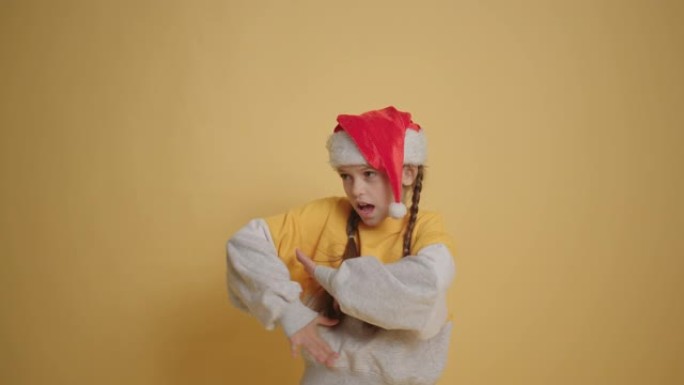 戴着圣诞老人帽子的小女孩在黄墙背景慢动作中读诗