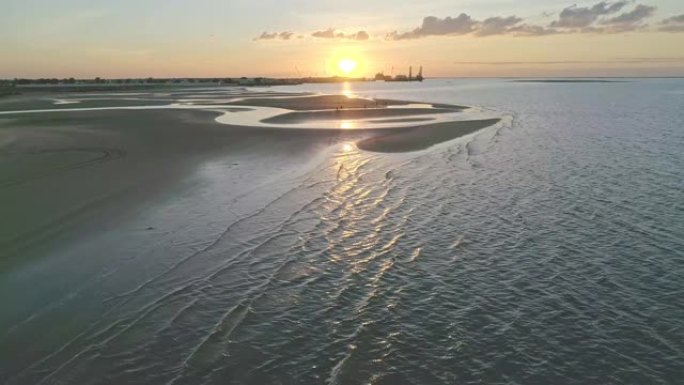 沙漠中的海滩日落显示石油钻井平台