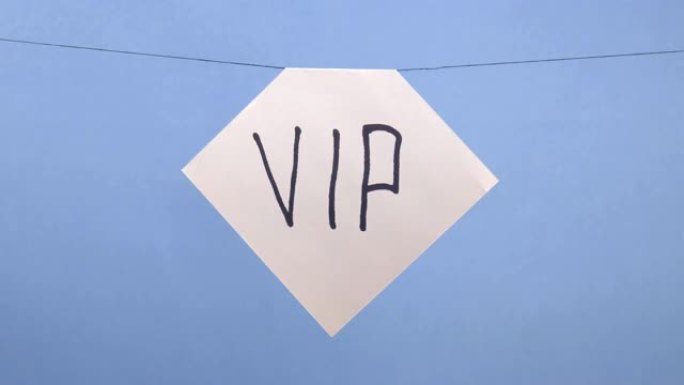 一名男子在蓝色背景上悬挂一张白色纸，上面刻有黑色题词 “vip”