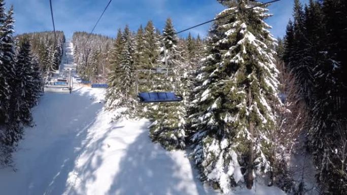 来自松树林和索道上滑雪者之间的滑雪椅升降机的POV