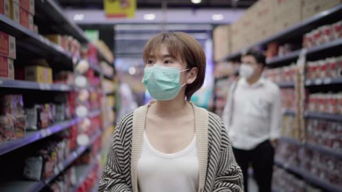 亚洲女性在超市购物，带面罩保护