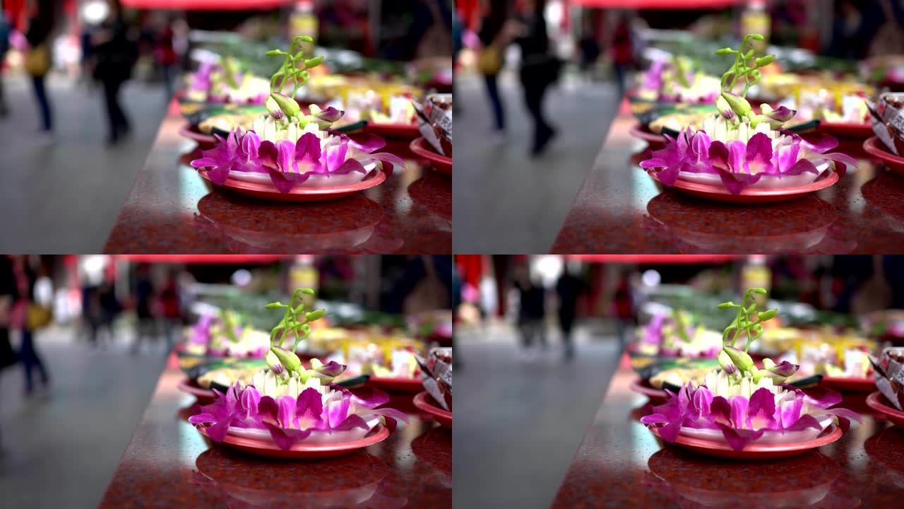 亚洲寺庙祭祀用的花。模糊的背景是朝拜者经过。