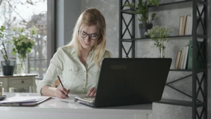 在线服务，一位成功的女企业家在办公室的电脑上工作，鲜花检查在线订单送花，小企业