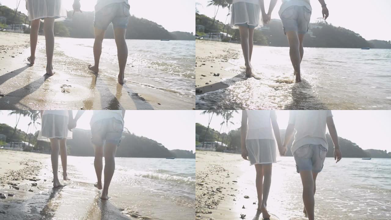 夏天，母亲和女儿在阳光普照的沙滩上快乐地散步和手拉手。爱的表达。