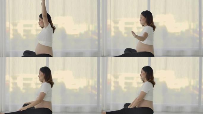 怀孕的亚洲妇女在卧室的柔软阳光下在垫子上做瑜伽运动，以获得良好的身体和精神卫生。母亲在子宫里照顾孩子