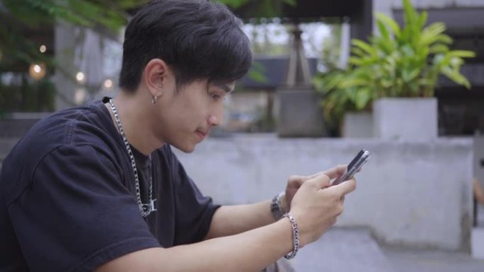 亚洲男子在咖啡馆使用智能手机等待朋友