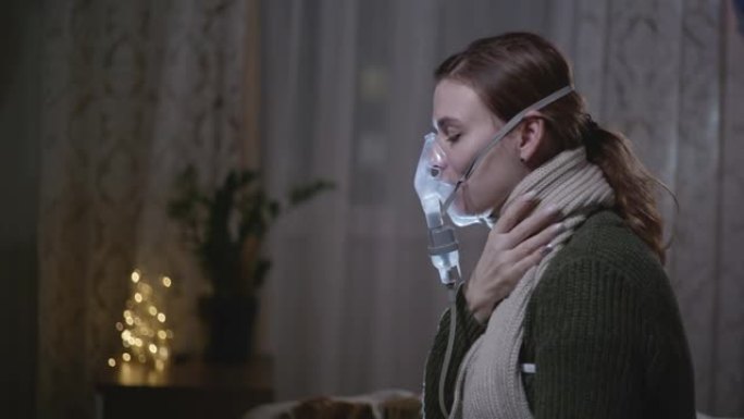 疾病，健康状况不佳的女孩坐在床上时通过吸入器面罩检查温度并呼吸