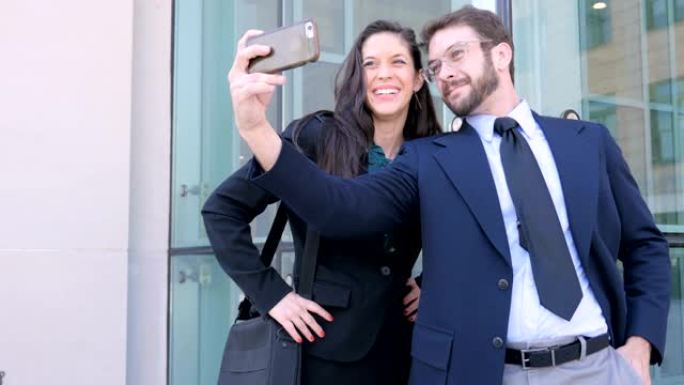 有吸引力的商务夫妇在办公楼外用手机自拍