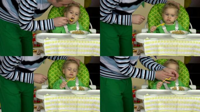 父亲学习女婴用勺子吃稀粥坐在高脚椅上。4K