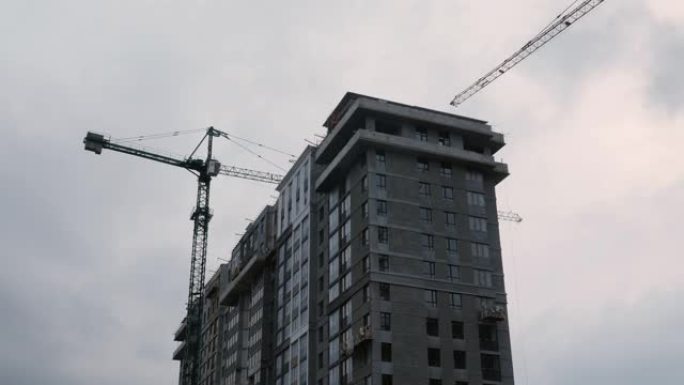 在建筑工地工作的工人。绿区公寓楼建设。孤立的住宅区正在建设中，以抵御灰色的天空