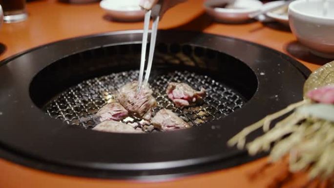 年轻的亚洲夫妇在日本火上吃和煮和牛牛肉。