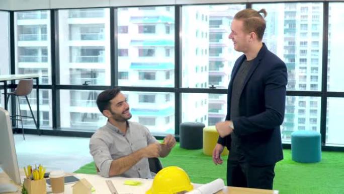 4k年轻的高加索专业建筑师设计师和同事在现代办公室完成创意项目工作后，一起握拳。在办公室工作的年轻建