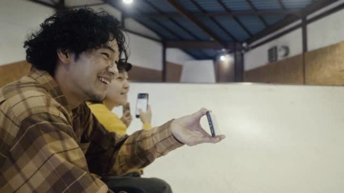 微笑的日本少年在坡道上拍摄他的朋友滑板 (慢动作)