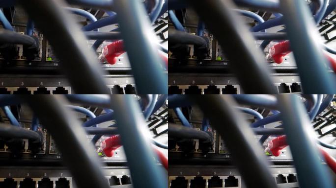缠结的Cat5e以太网电缆插入闪烁的网络交换机中，在信息技术网络壁橱的后台使用凌乱的高速互联网千兆C