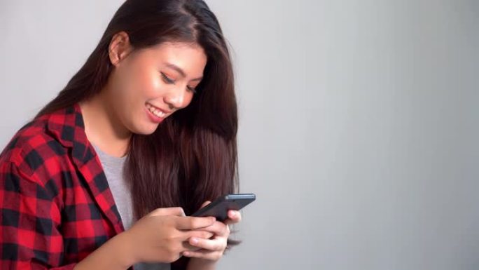 美丽的亚洲女人通过互联网在线服务在国外的智能手机上与男朋友或朋友聊天。漂亮女孩想念和爱的男朋友。与家