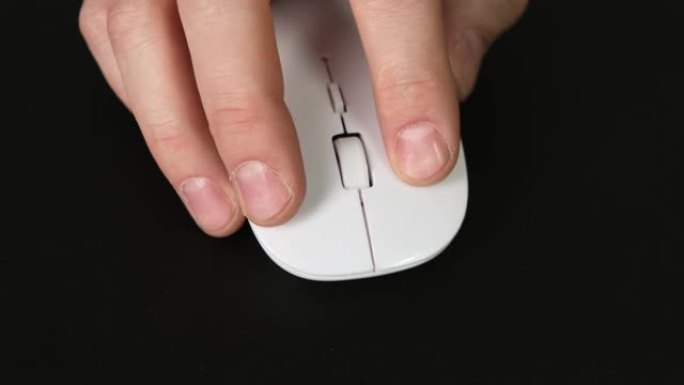 Man hand在黑色桌子上使用白色无线鼠标。