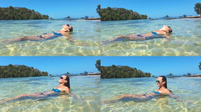 热带概念视频。棕色皮肤的年轻女子躺在岛屿背景的海浪上。