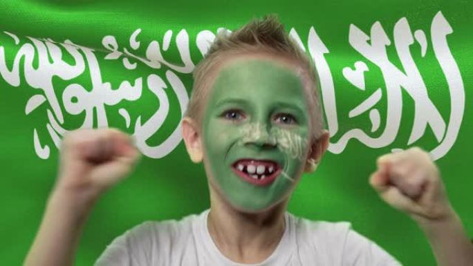沙特阿拉伯国旗背景上的快乐粉丝。有着民族色彩的脸的快乐男孩。