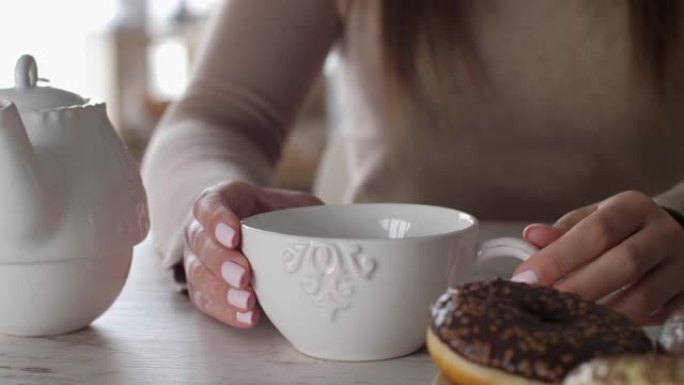 享受甜甜圈和新鲜茶的年轻女子的中段