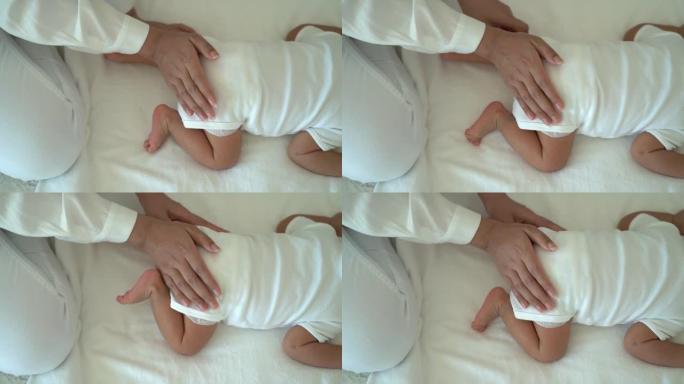 从照顾妈妈和新生母亲拍拍婴儿亚洲小孩躺在家里卧室的肚子上