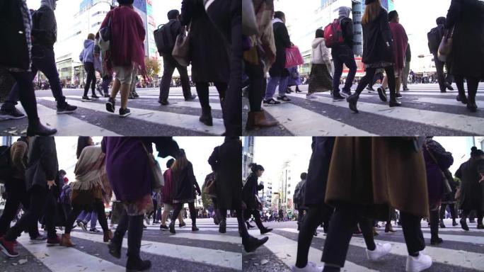 高清慢动作低角度视角拥挤行人的城市景观男女游客步行穿越涩谷街人行横道，交通信号灯在日本东京市涩谷的道