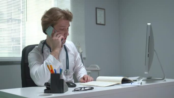 医生坐在医院的桌子旁打电话