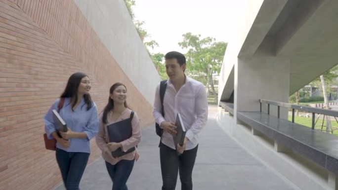 亚洲三名学生在大学休息期间在大学礼堂一起散步和交谈。教育，学习，学生，校园，大学，生活方式概念。