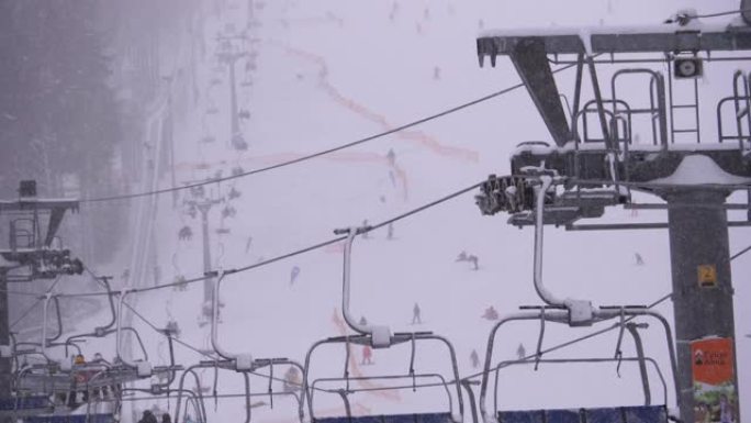 滑雪胜地的滑雪缆车，慢动作。滑雪者爬上滑雪椅电梯，爬到下雪坡