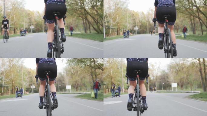 骑自行车的女骑车人的腿踩着自行车。后退射击。自行车上的腿部肌肉。自行车概念。