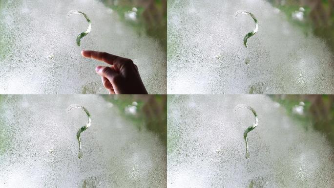 女人的手在雾蒙蒙的玻璃上画问号