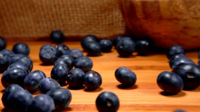 成熟的蓝莓在桌子的木制表面上滚动