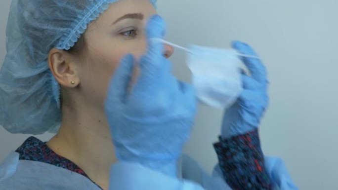 妇女脱下防护医用口罩的肖像，特写。年轻女科学家摘下医用蓝色口罩。外科治疗后医生取下防护面罩
