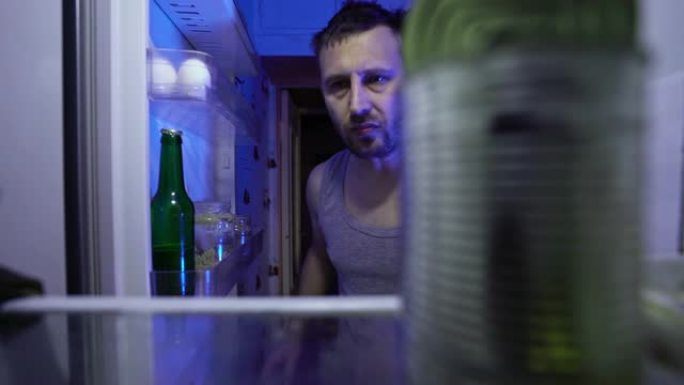 在冰箱里找食物的人。那家伙在冰箱里吃剩下的食物，然后拿了一瓶啤酒。