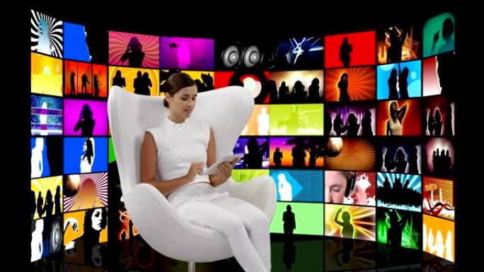 女人坐在白色椅子上，并在屏幕上播放视频