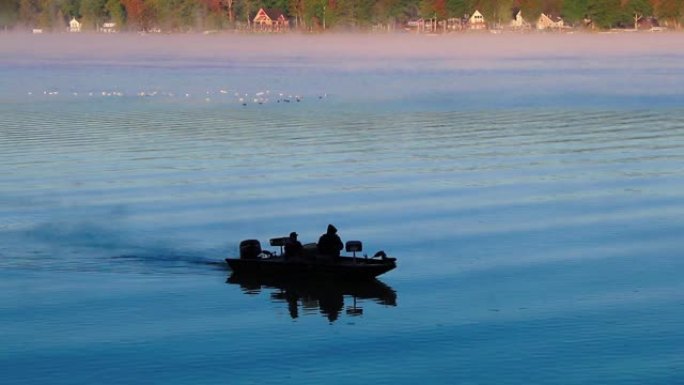 渔船的Silouette在宁静宁静的早晨在日出起雾时经过