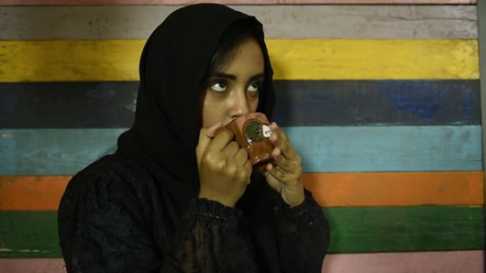 年轻漂亮的穆斯林女孩戴着头巾拿着陶瓷茶杯