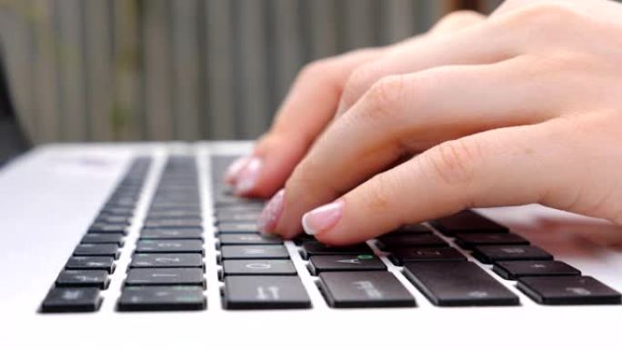 女性手在笔记本键盘上打字。在户外笔记本电脑工作的面目全非的女人。女孩和某人聊天或浏览互联网。使用电脑