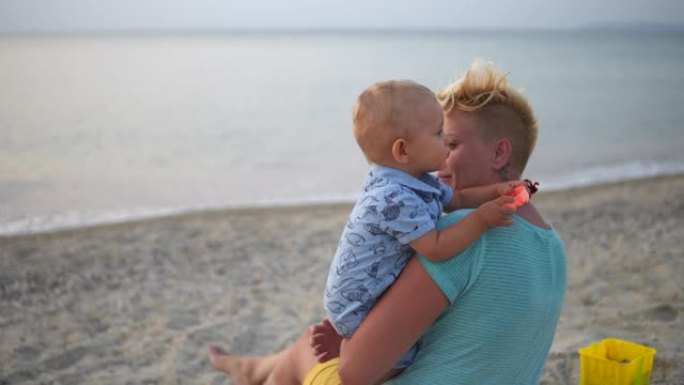 妈妈抱着男孩在海滩上