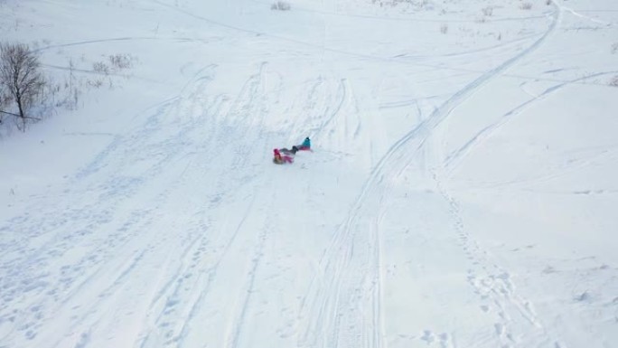 一家人骑在雪山上。从高处射击。白雪皑皑的冬季景观。户外运动